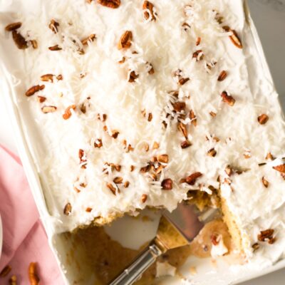coconut pecan poke cake in pan with spatula