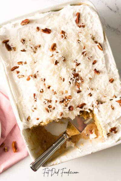 coconut pecan poke cake in pan with spatula